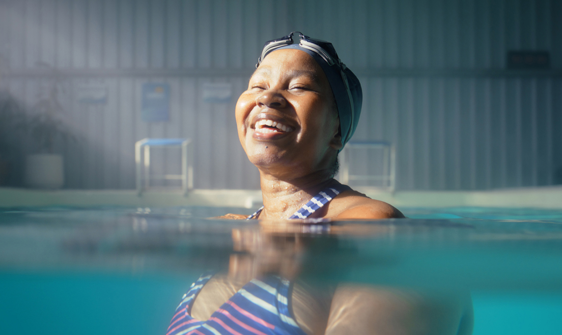 Senior, black woman and happy in swimming pool for physical therapy.